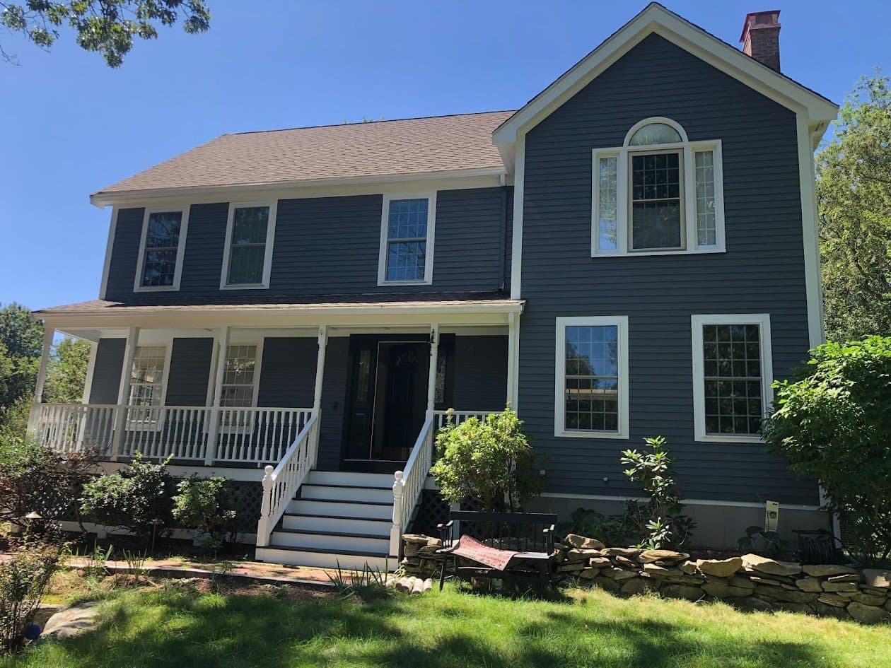 A navy blue colonial home in Massachusetts with freshly painted exterior siding, crisp white trim, and a clean front entrance