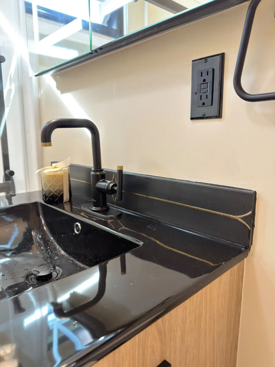Close-up of black vanity sink with gold veining and matte black faucet